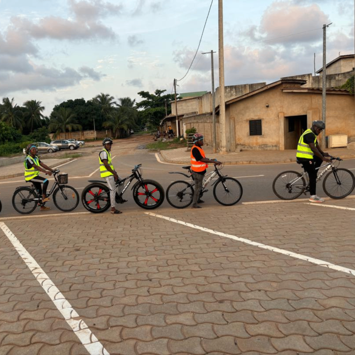 Semaine 4 · Groupe de riders After6 en gilets fluo alignés avec leurs vélos au départ à Calavi