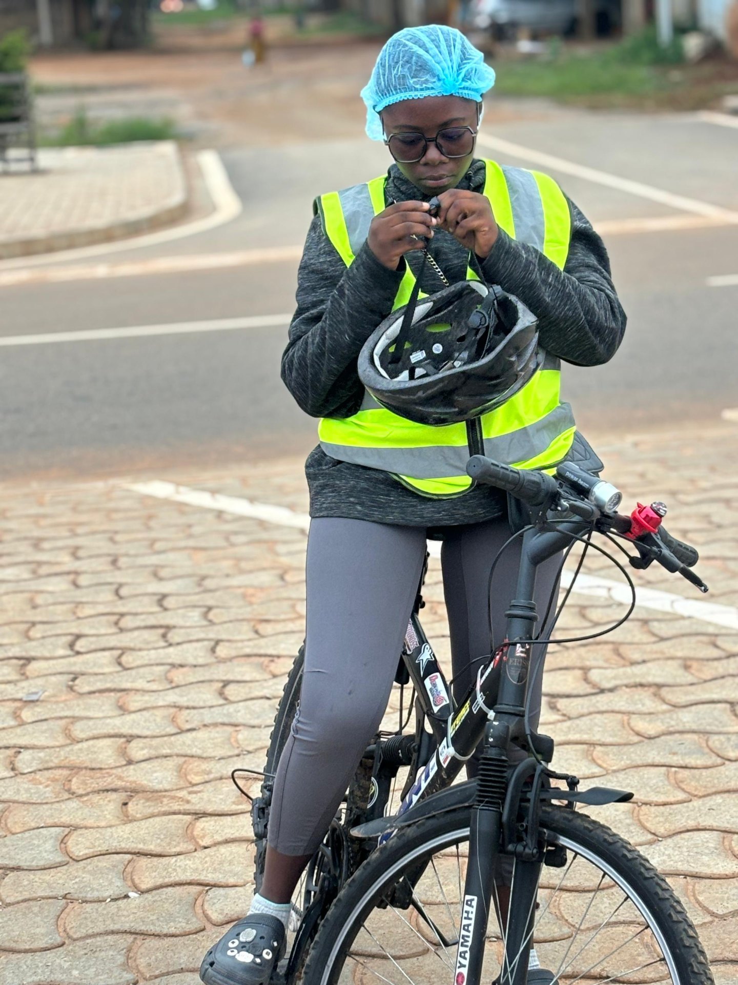 Semaine 3 · Rideuse After6 ajustant sa jugulaire de casque sur son vélo