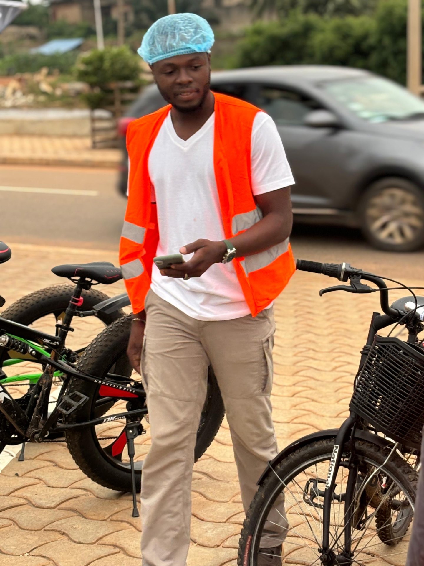 Semaine 3 · Rider After6 en gilet orange consulte son téléphone entre les vélos